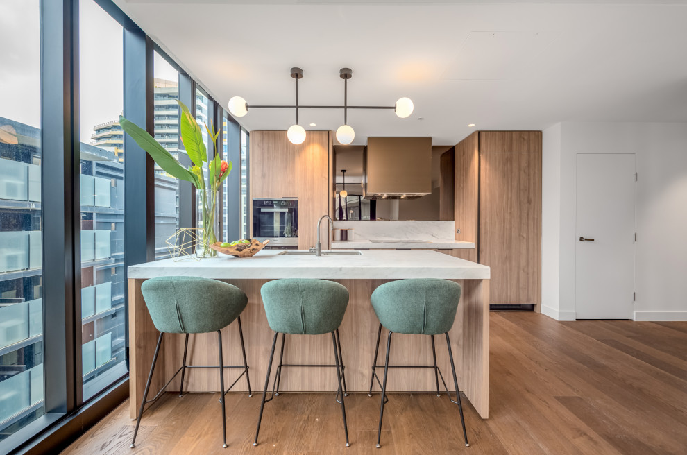 Mittelgroße Moderne Küche mit Doppelwaschbecken, Marmor-Arbeitsplatte, Küchenrückwand in Weiß, schwarzen Elektrogeräten, brauner Arbeitsplatte und braunem Holzboden in Melbourne