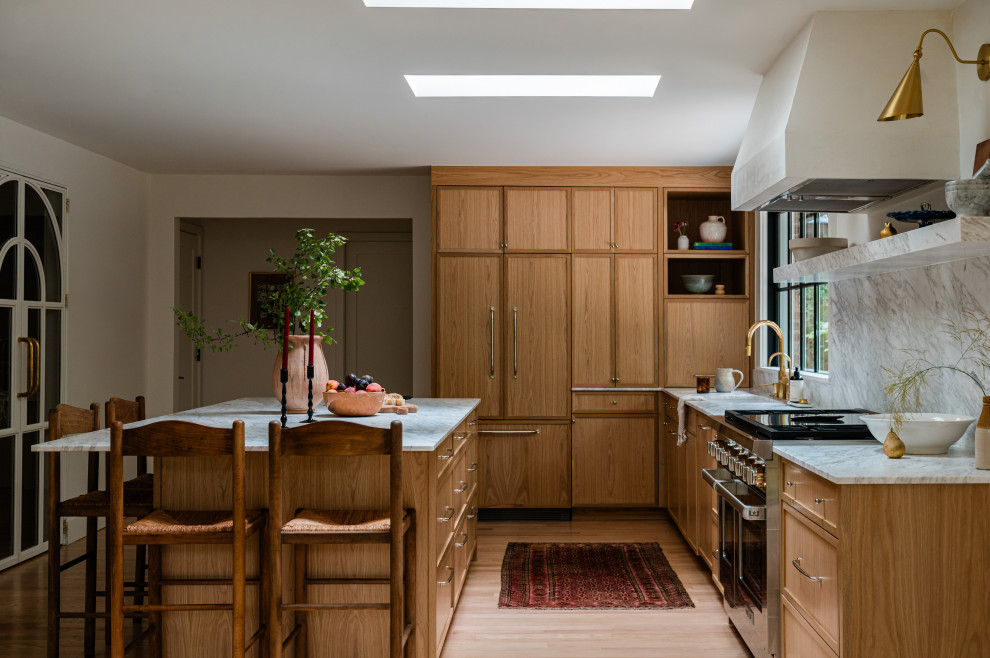 Example of a mid-sized transitional l-shaped light wood floor eat-in kitchen design in Chicago with an undermount sink, shaker cabinets, light wood cabinets, marble countertops, white backsplash, marble backsplash, paneled appliances, an island and white countertops