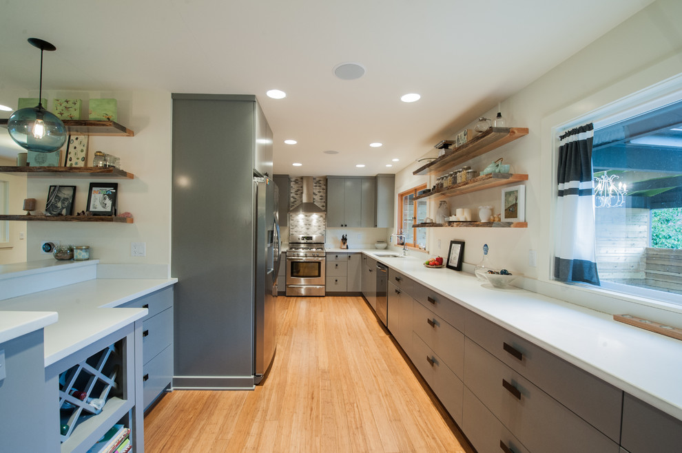 Design ideas for a mid-sized midcentury u-shaped kitchen in Portland with an undermount sink, flat-panel cabinets, grey cabinets, concrete benchtops, white splashback, cement tile splashback, stainless steel appliances and bamboo floors.