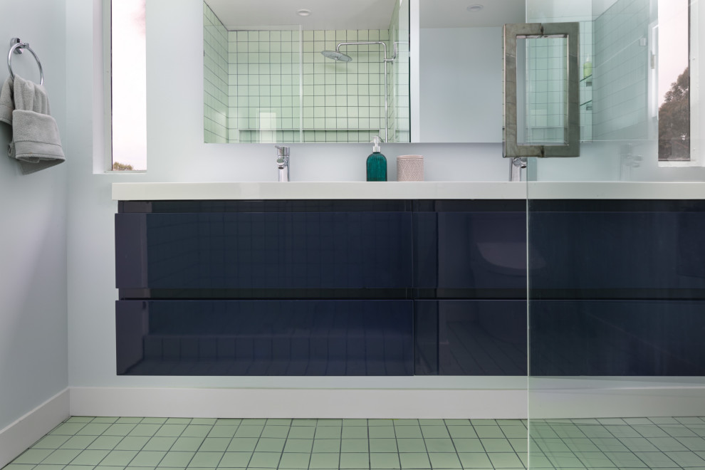 Foto på ett litet funkis vit en-suite badrum, med släta luckor, blå skåp, en dusch i en alkov, en bidé, grön kakel, porslinskakel, vita väggar, klinkergolv i porslin, ett integrerad handfat, bänkskiva i akrylsten, grönt golv och dusch med gångjärnsdörr