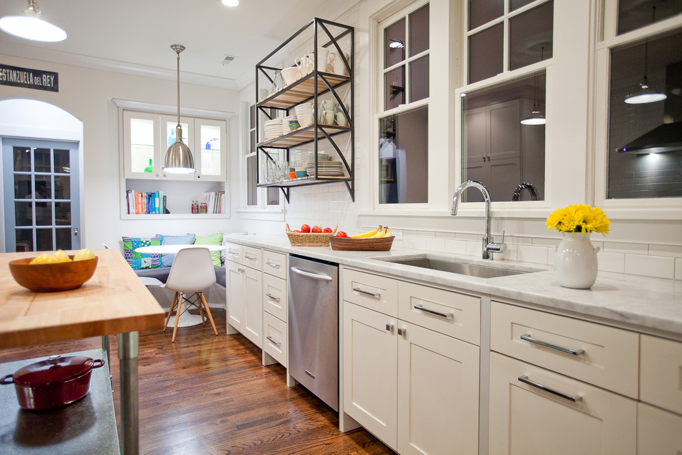Large contemporary galley kitchen in New York with an undermount sink, shaker cabinets, white cabinets, white splashback, stainless steel appliances, marble benchtops, medium hardwood floors and with island.