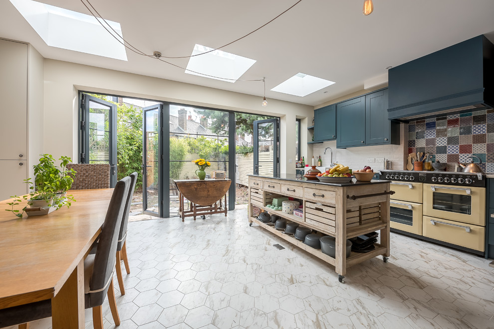 Design ideas for a mid-sized contemporary eat-in kitchen in London with a farmhouse sink, blue cabinets, multi-coloured splashback, ceramic splashback, marble floors, with island and multi-coloured floor.