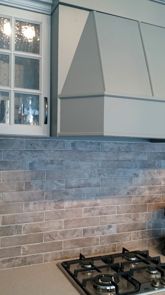 Kitchen - mid-sized transitional single-wall kitchen idea in Toronto with an undermount sink, recessed-panel cabinets, gray cabinets, quartz countertops, gray backsplash, stone tile backsplash, stainless steel appliances and an island