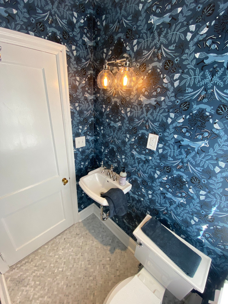 Small classic cloakroom in Philadelphia with a one-piece toilet, blue walls, a wall-mounted sink, grey floors and wallpapered walls.