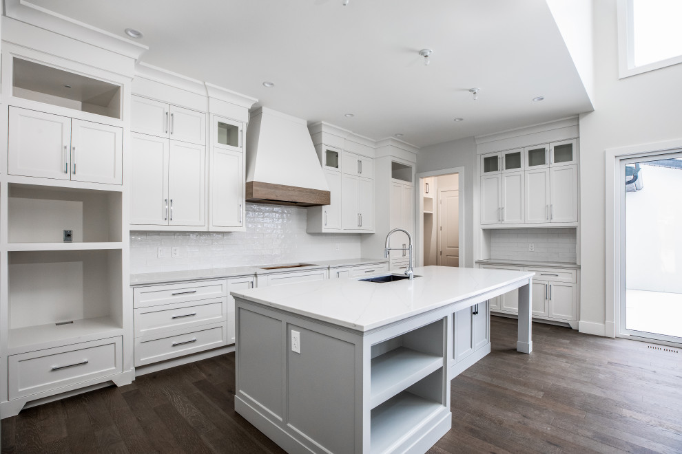 Inspiration for a mid-sized country u-shaped eat-in kitchen in Calgary with an undermount sink, recessed-panel cabinets, white cabinets, marble benchtops, white splashback, ceramic splashback, stainless steel appliances, dark hardwood floors, with island, brown floor and white benchtop.