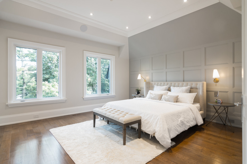 Mid-sized transitional master bedroom in Toronto with grey walls, medium hardwood floors, brown floor, vaulted, panelled walls, a standard fireplace and a stone fireplace surround.