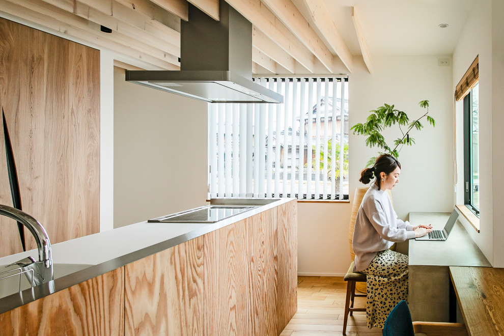 Foto di una cucina contemporanea con top in superficie solida, elettrodomestici neri, pavimento in legno massello medio e travi a vista
