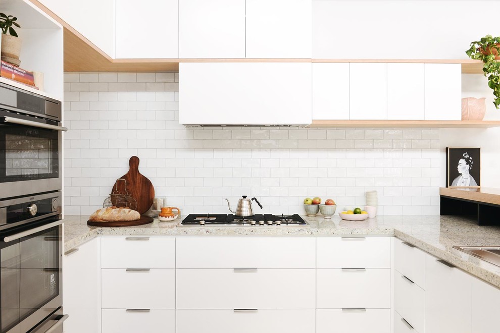 Mid-sized scandinavian u-shaped eat-in kitchen in Melbourne with a double-bowl sink, flat-panel cabinets, white cabinets, granite benchtops, white splashback, ceramic splashback, stainless steel appliances and light hardwood floors.