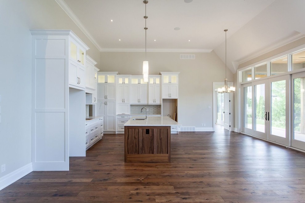 Inspiration for a large transitional l-shaped dark wood floor and brown floor eat-in kitchen remodel with a double-bowl sink, shaker cabinets, medium tone wood cabinets, quartz countertops, gray backsplash, glass tile backsplash, stainless steel appliances, an island and white countertops