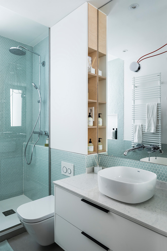 Photo of a contemporary 3/4 bathroom in Madrid with flat-panel cabinets, white cabinets, blue tile, green tile, a vessel sink, grey floor, a hinged shower door, a corner shower, a wall-mount toilet, mosaic tile, white walls and white benchtops.