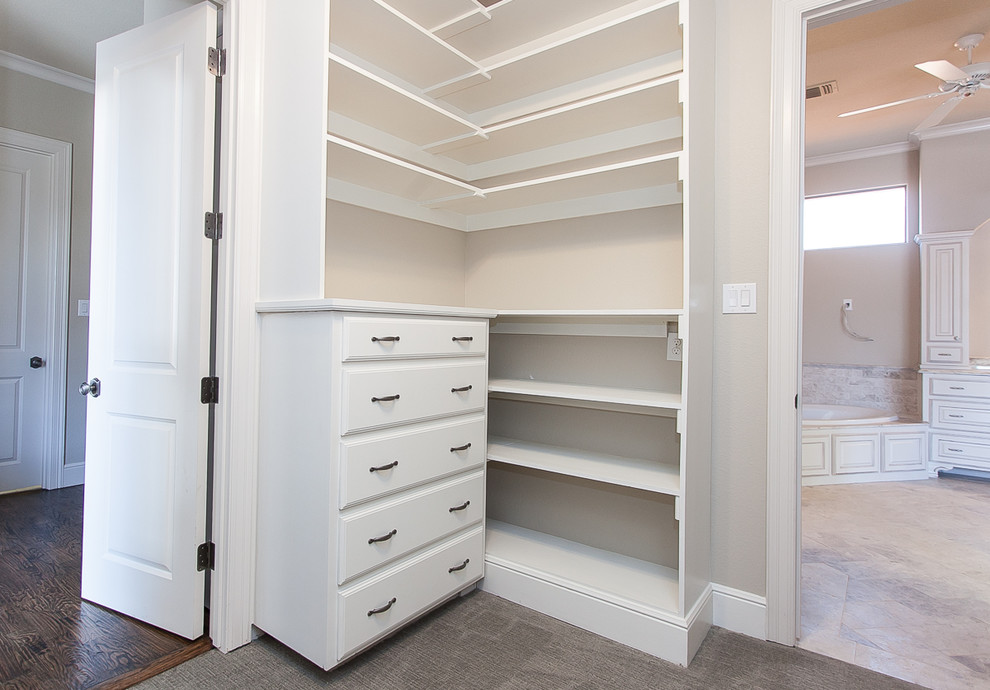Large transitional gender-neutral walk-in wardrobe in Dallas with raised-panel cabinets, white cabinets and carpet.