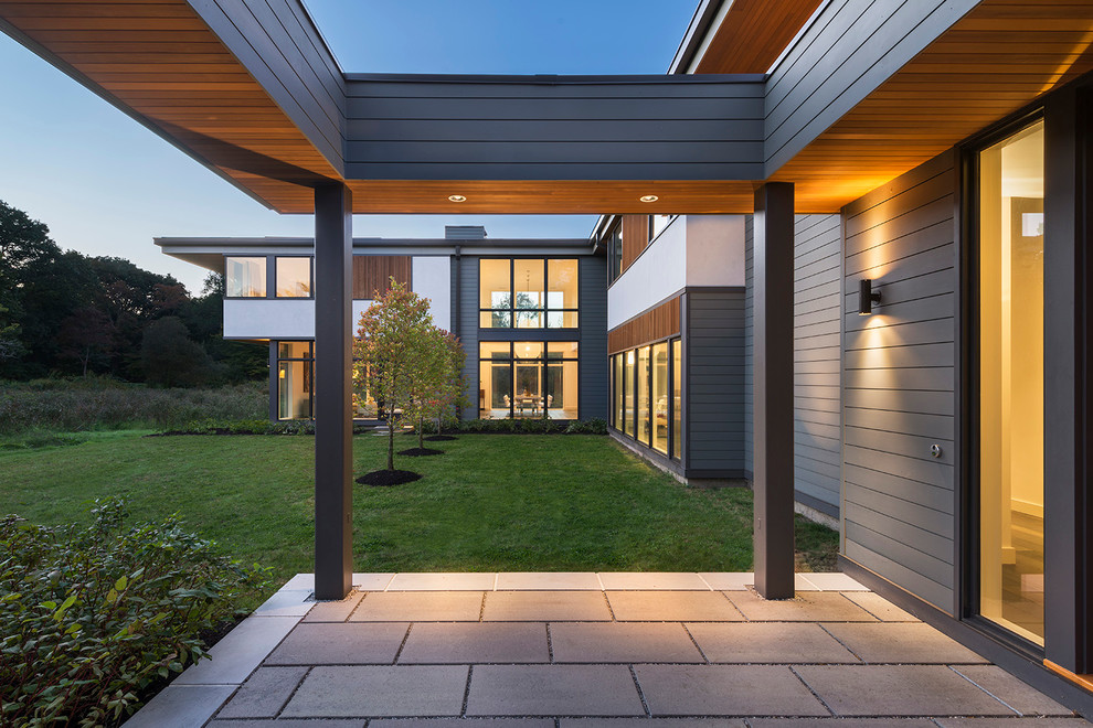 This is an example of a large contemporary two-storey grey exterior in Boston with mixed siding and a flat roof.