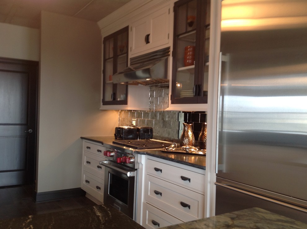 Example of a large transitional galley medium tone wood floor eat-in kitchen design in Milwaukee with white cabinets, granite countertops, gray backsplash, stainless steel appliances, a peninsula, a double-bowl sink, recessed-panel cabinets and mirror backsplash