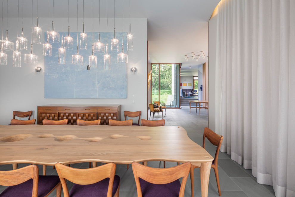 Cette image montre une grande salle à manger minimaliste fermée avec un mur blanc, un sol en calcaire et un sol bleu.