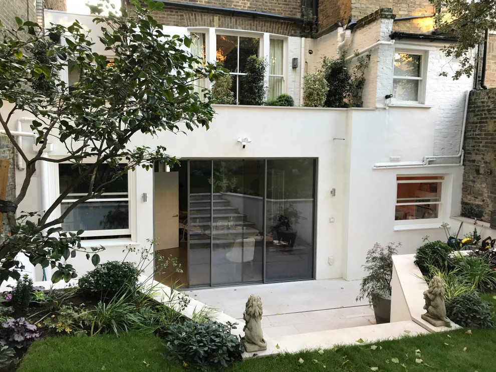 This is an example of a mid-sized modern one-storey white apartment exterior in London with painted brick siding, a flat roof, a tile roof and a brown roof.