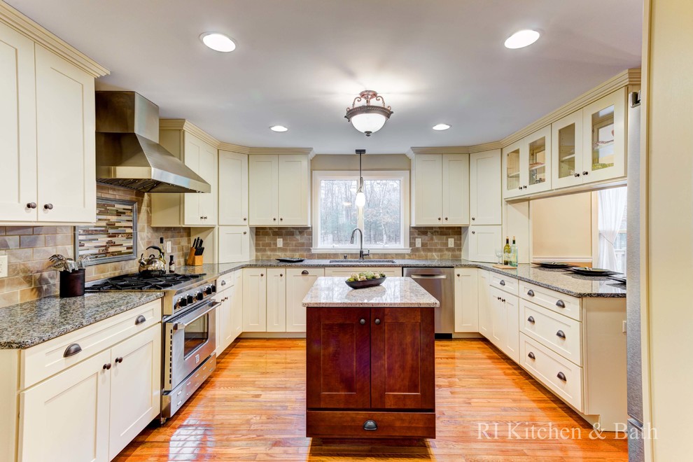 This is an example of a large transitional u-shaped eat-in kitchen in Providence with an undermount sink, shaker cabinets, beige cabinets, granite benchtops, brown splashback, porcelain splashback, stainless steel appliances, light hardwood floors and with island.