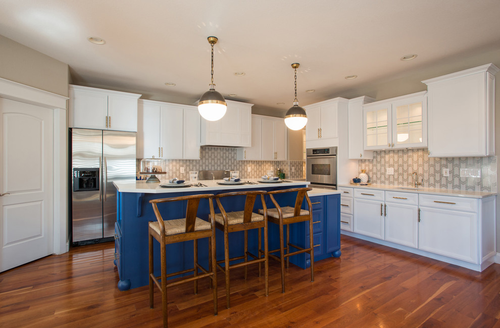 This is an example of a mid-sized eclectic l-shaped open plan kitchen in Denver with an undermount sink, shaker cabinets, white cabinets, quartz benchtops, multi-coloured splashback, cement tile splashback, stainless steel appliances, medium hardwood floors, with island and brown floor.