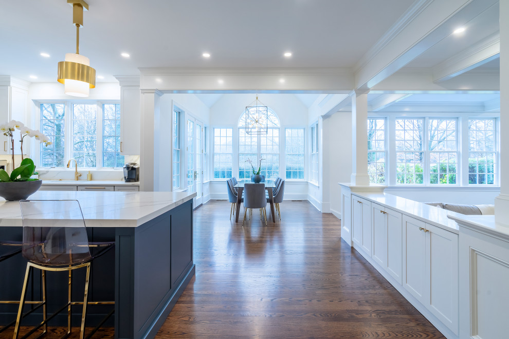 Design ideas for a large transitional open plan kitchen in Philadelphia with an undermount sink, shaker cabinets, white cabinets, quartz benchtops, white splashback, engineered quartz splashback, stainless steel appliances, dark hardwood floors, with island, brown floor and white benchtop.