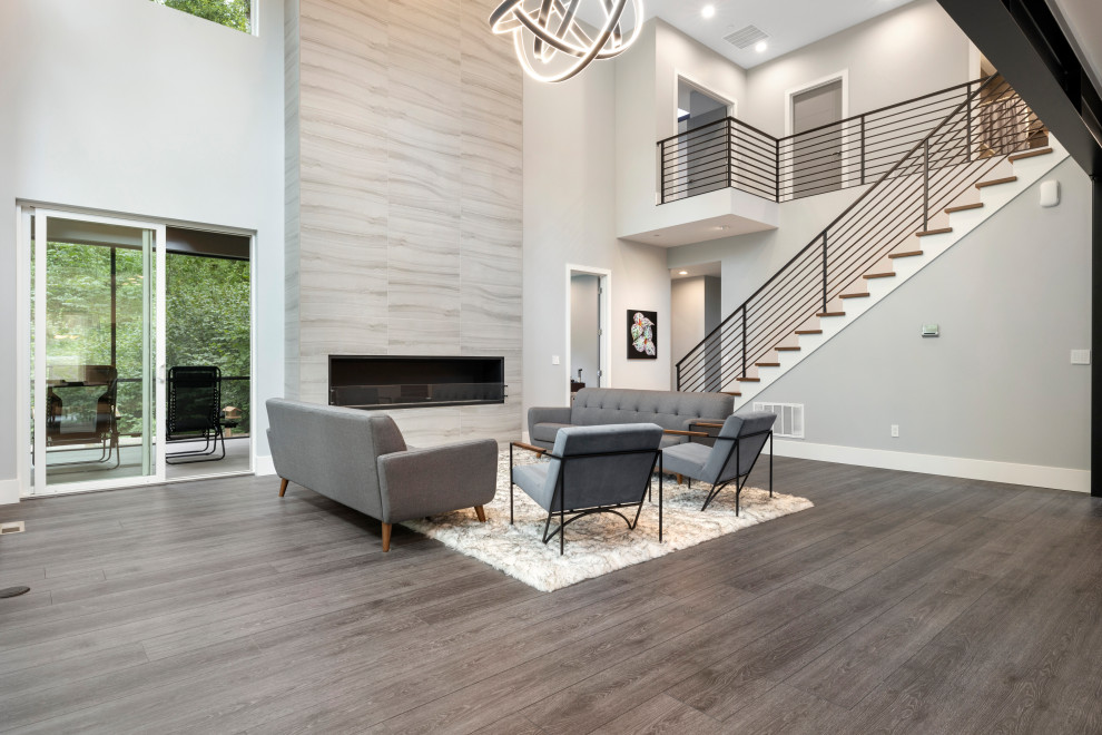Example of a large minimalist formal and open concept vinyl floor, gray floor and vaulted ceiling living room design in Seattle with gray walls, a standard fireplace and a stone fireplace