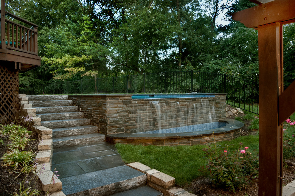 Design ideas for a mid-sized country backyard l-shaped lap pool in Chicago with a water feature and natural stone pavers.