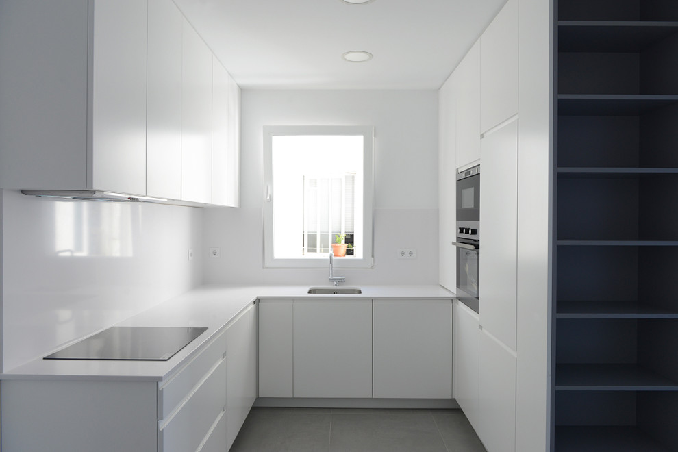Photo of a small scandinavian l-shaped open plan kitchen in Madrid with an undermount sink, flat-panel cabinets, white cabinets, white splashback, stainless steel appliances, ceramic floors and no island.