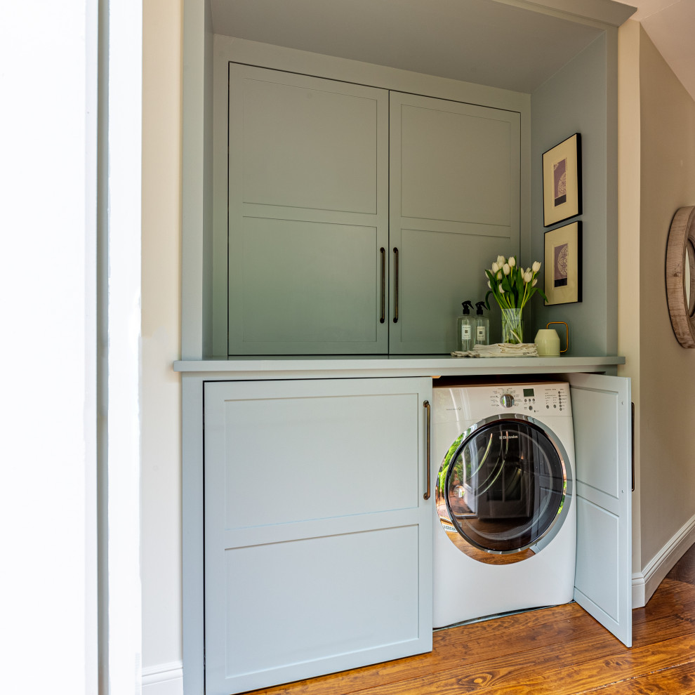 Inspiration for a small transitional galley laundry cupboard in Bridgeport with shaker cabinets, grey cabinets, wood benchtops, white walls, medium hardwood floors, a side-by-side washer and dryer and grey benchtop.