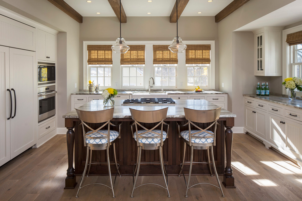 Photo of a beach style kitchen in Minneapolis with a farmhouse sink, recessed-panel cabinets, white cabinets, panelled appliances, light hardwood floors, with island, beige floor and grey benchtop.