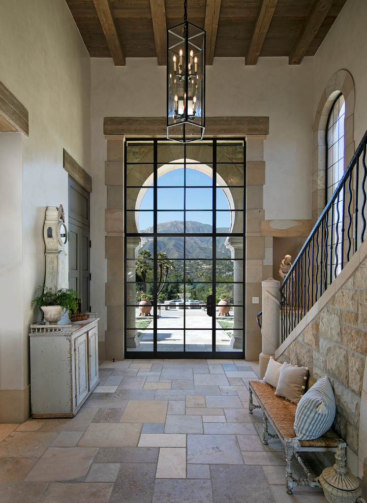 Design ideas for a mediterranean entry hall in Santa Barbara with white walls, a single front door, a glass front door and beige floor.