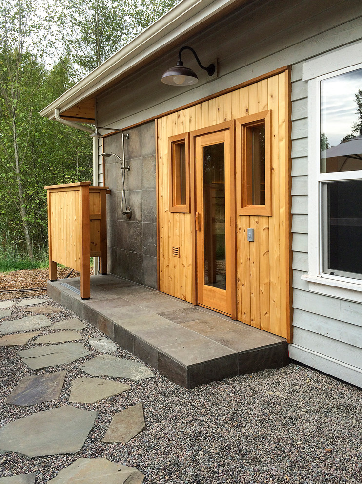 This is an example of a mid-sized contemporary backyard patio in Seattle with an outdoor shower, gravel and a roof extension.