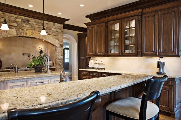 This is an example of a large traditional u-shaped separate kitchen in Atlanta with a double-bowl sink, raised-panel cabinets, dark wood cabinets, quartzite benchtops, beige splashback, ceramic splashback, stainless steel appliances, dark hardwood floors, with island, multi-coloured floor and beige benchtop.