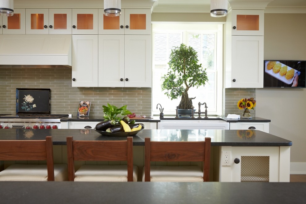 Inspiration for a mid-sized transitional galley medium tone wood floor and brown floor eat-in kitchen remodel in Grand Rapids with a farmhouse sink, shaker cabinets, white cabinets, soapstone countertops, gray backsplash, matchstick tile backsplash, stainless steel appliances and an island