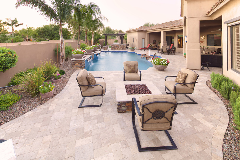 Design ideas for a large mediterranean backyard custom-shaped natural pool in Phoenix with natural stone pavers.