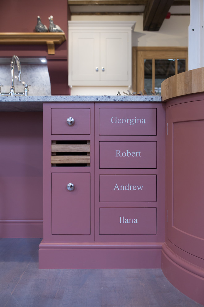 This is an example of a medium sized classic l-shaped open plan kitchen with a belfast sink, shaker cabinets, white cabinets, granite worktops and an island.