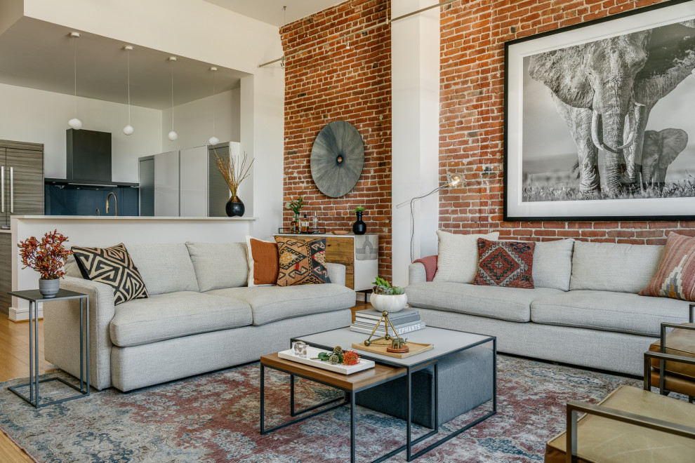 Inspiration for a mid-sized contemporary loft-style living room in San Francisco with white walls, brick walls, light hardwood floors and brown floor.