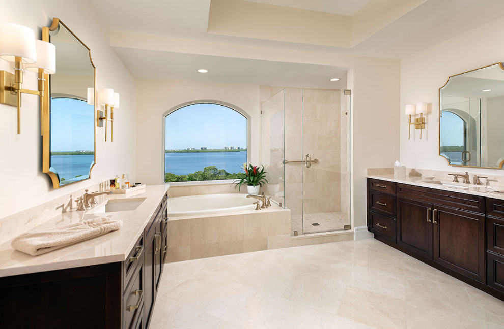 Photo of a large contemporary master bathroom in Miami with recessed-panel cabinets, brown cabinets, a drop-in tub, an alcove shower, a two-piece toilet, beige tile, marble, beige walls, marble floors, an undermount sink, marble benchtops, beige floor, a hinged shower door, beige benchtops, a single vanity, a built-in vanity and recessed.