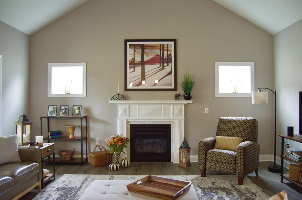 На фото: открытая гостиная комната среднего размера с бежевыми стенами, полом из ламината, стандартным камином, фасадом камина из плитки, отдельно стоящим телевизором, коричневым полом и сводчатым потолком