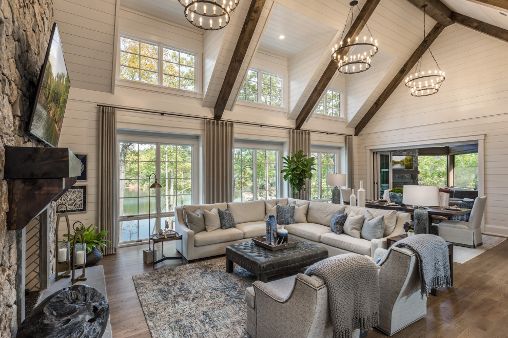 Large rustic open plan living room in Other with medium hardwood flooring, a standard fireplace, a stone fireplace surround, a wall mounted tv, brown floors, a vaulted ceiling and tongue and groove walls.