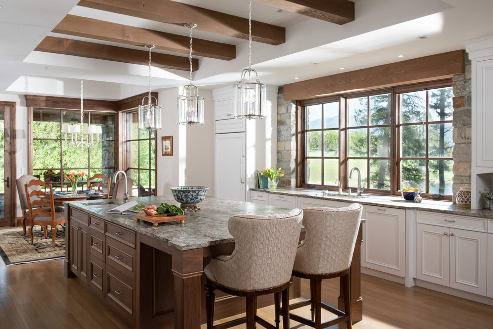 Mountain style light wood floor and exposed beam eat-in kitchen photo with recessed-panel cabinets, white cabinets, paneled appliances, an island and gray countertops