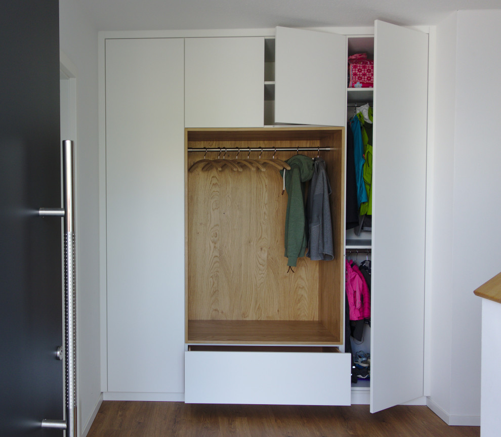 This is an example of a small modern mudroom in Nuremberg with white walls, light hardwood floors and wallpaper.
