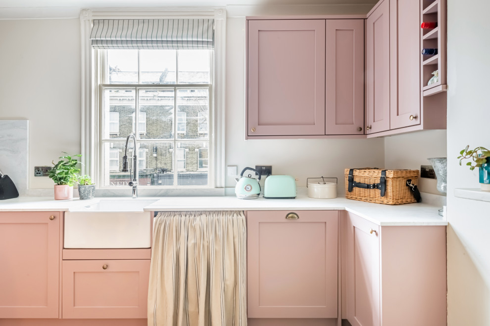 Immagine di una cucina ad U eclettica di medie dimensioni con ante in stile shaker, ante rosa, top in superficie solida e top bianco