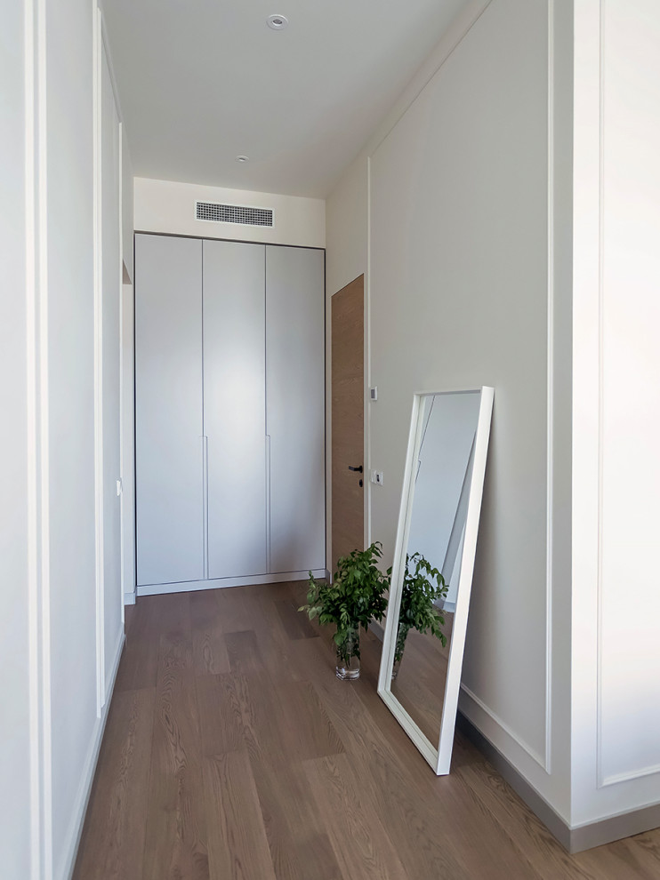 На фото: узкий коридор в современном стиле с белыми стенами и светлым паркетным полом с
