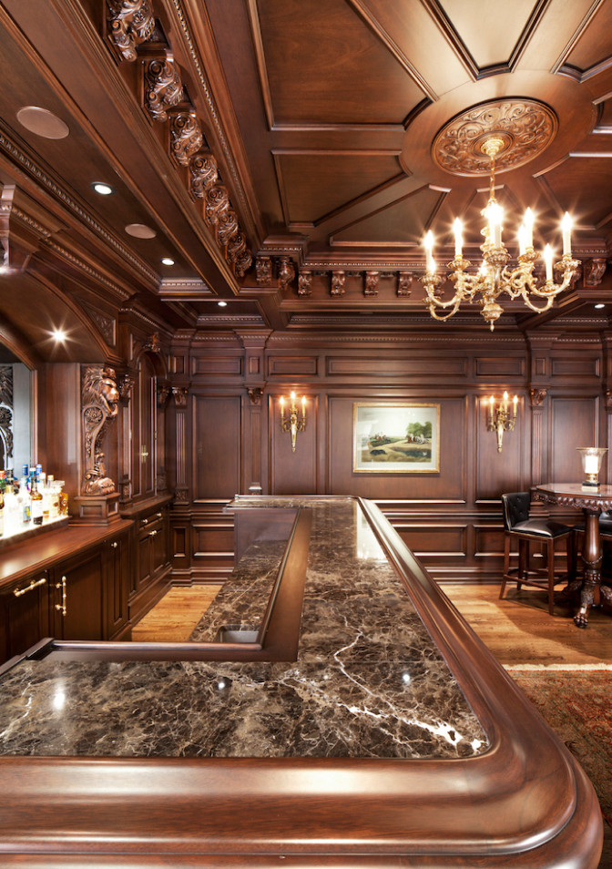 Photo of a large traditional u-shaped seated home bar in DC Metro with an integrated sink, shaker cabinets, dark wood cabinets, quartz benchtops, mirror splashback, medium hardwood floors, brown floor and brown benchtop.