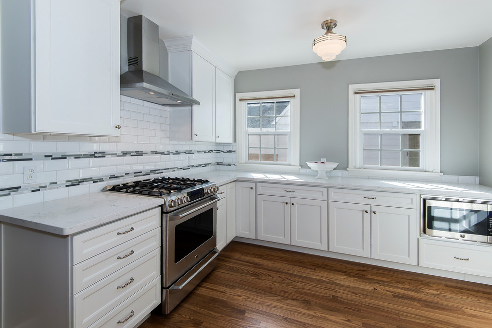 Enclosed kitchen - mid-sized transitional medium tone wood floor enclosed kitchen idea with a farmhouse sink, recessed-panel cabinets, white cabinets, granite countertops, white backsplash, subway tile backsplash, stainless steel appliances and no island