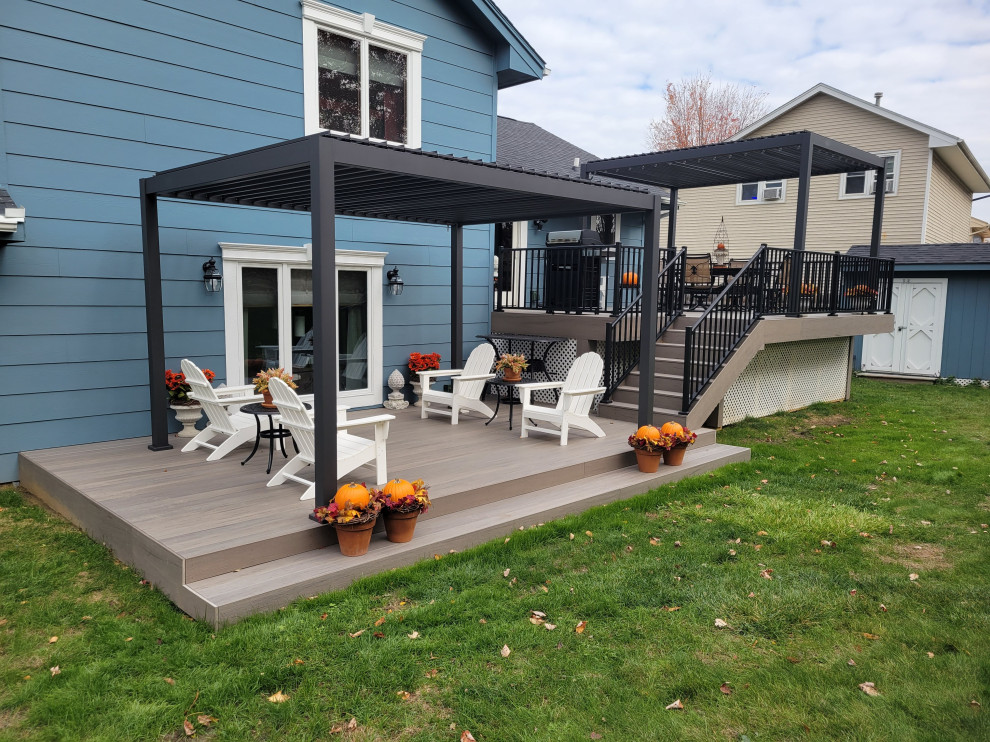 Large backyard ground level metal railing deck photo with a pergola