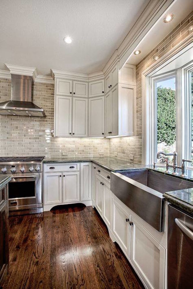 Inspiration for a large transitional u-shaped dark wood floor and brown floor kitchen remodel in Phoenix with a farmhouse sink, recessed-panel cabinets, white cabinets, granite countertops, gray backsplash, subway tile backsplash, stainless steel appliances and an island