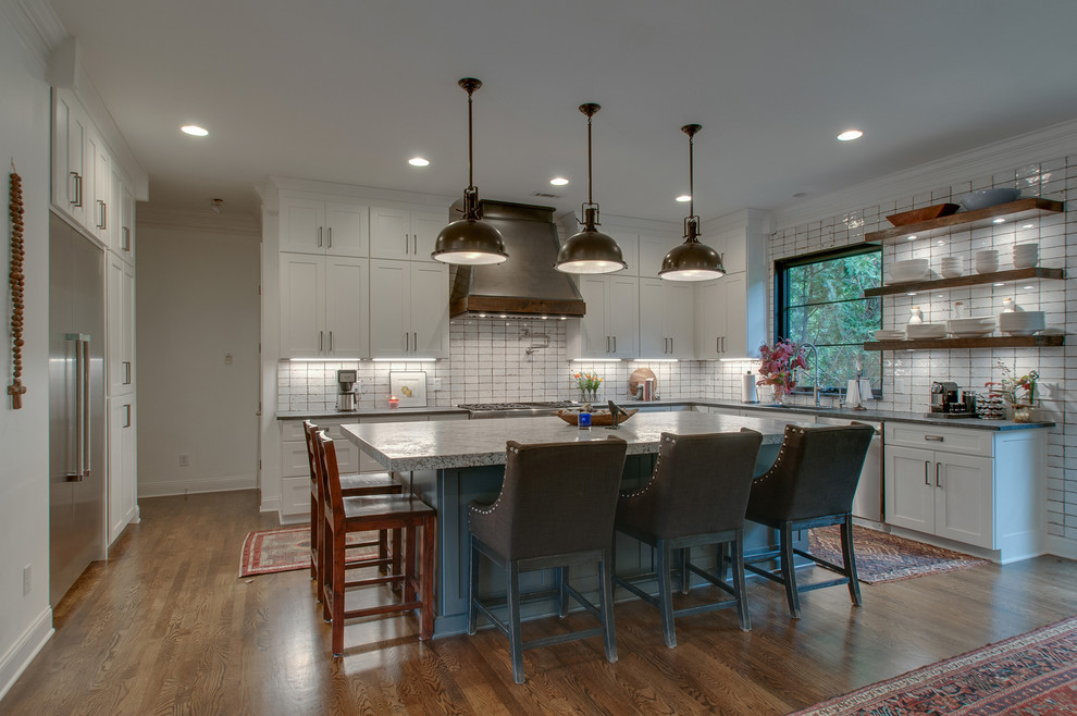Inspiration for a mid-sized traditional open plan kitchen in Nashville with an undermount sink, shaker cabinets, white cabinets, granite benchtops, white splashback, ceramic splashback, stainless steel appliances, medium hardwood floors, with island, brown floor and grey benchtop.