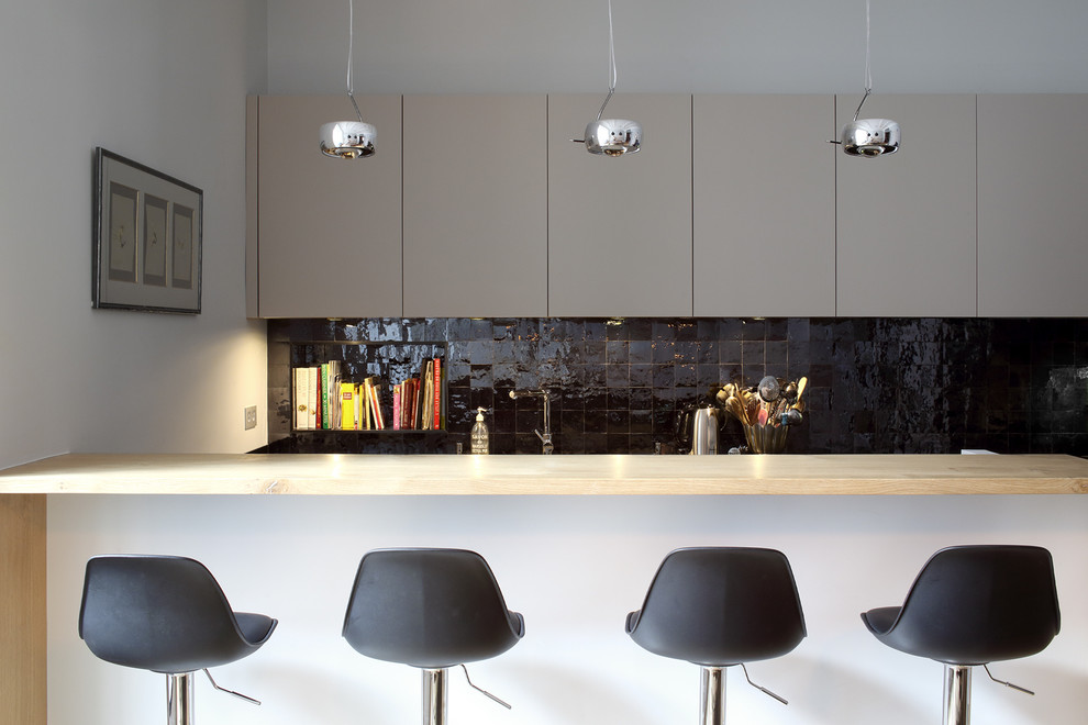 Photo of a mid-sized contemporary galley eat-in kitchen in Paris with an undermount sink, flat-panel cabinets, granite benchtops, black splashback, ceramic splashback, stainless steel appliances, ceramic floors and with island.