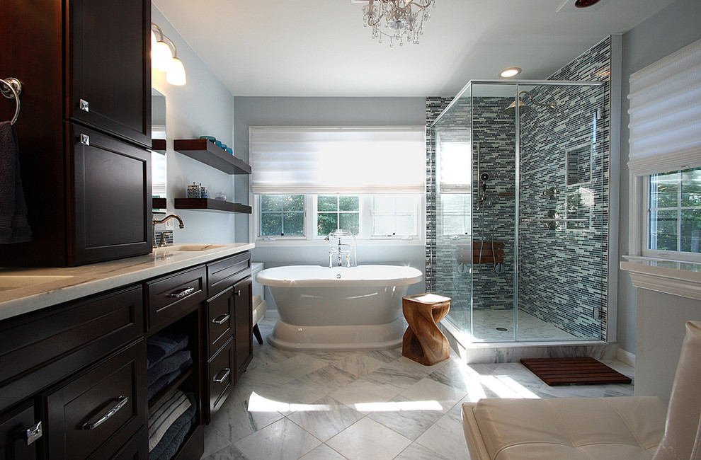 This is an example of a mid-sized traditional master bathroom in DC Metro with shaker cabinets, dark wood cabinets, a freestanding tub, a corner shower, black and white tile, blue tile, gray tile, mosaic tile, blue walls, marble floors, an undermount sink and marble benchtops.