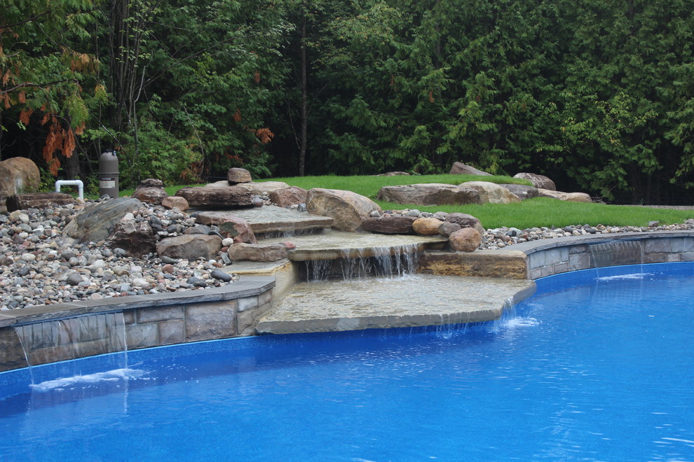 Inspiration for a large contemporary backyard kidney-shaped natural pool in Ottawa with a water feature and stamped concrete.