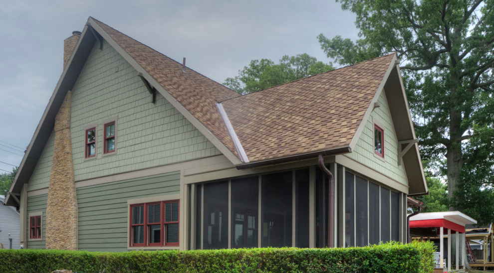 Esempio della villa piccola verde american style a due piani con rivestimento con lastre in cemento, tetto a capanna, copertura a scandole, tetto marrone e con scandole